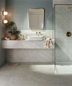 a bathroom with marble counter tops and white tile on the walls, along with a walk in shower