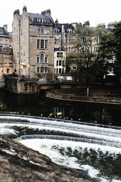 a river running through a city with tall buildings in the backgroung and water flowing from it