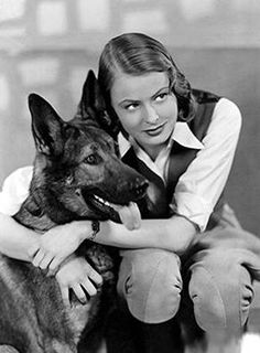 a woman sitting on a couch with her german shepard dog, who is looking at the camera