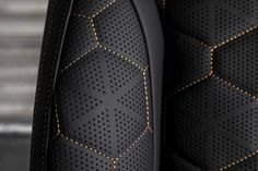 close up view of black leather with gold stitching on the back of a car seat