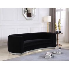 a black couch sitting on top of a white floor next to a mirror and lamp