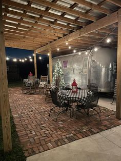 an outdoor patio with tables and chairs under a pergolated roof covered in lights