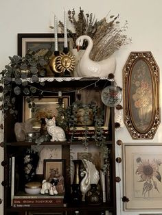 there is a shelf with pictures and other items on it in the corner, along with two swans