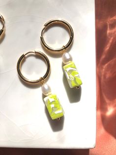 three pairs of gold hoop earrings with green and white beads