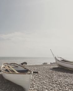 two boats sitting on the beach next to each other