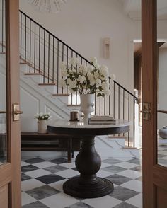 a vase with flowers sitting on top of a table in front of a stair case