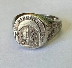 "if you're lucky enough to have the last name Fischer, here's a ring for you.  it seems a rare thing to have a ring with a family crest on it, and this is a pretty cool design, with stars and all kinds of room for interpretation.  it's sterling and has plenty of wear, mostly on the inner band.  the crest itself is pretty clear and i'm so curious why the letters F and R are upside down and the S is backwards. size:  6.75 height of face:  9/16\" width of inner band:  between 2 and 3/16\"" Signet Ring Family Crest, Family Crest Ring, Family Crest Rings, Horseshoe Ring, Family Rings, Signet Rings, Family Crest, Signet Ring, 10k Gold