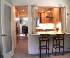 two stools are in front of the kitchen counter and door to the living room