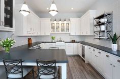 a large kitchen with white cabinets and black counter tops, along with wooden flooring