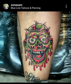 a tattoo on the leg of a person with a green and red zombie face painted on it