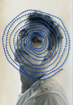 a man's head is surrounded by blue stringed objects in the shape of a spiral