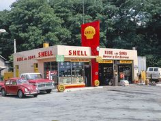 an old gas station with cars parked in front