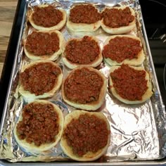 many small pizzas are sitting on top of tin foil and ready to be cooked