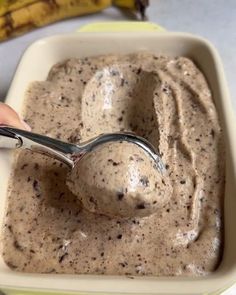 a spoon in a bowl filled with chocolate chip ice cream and bananas on the side