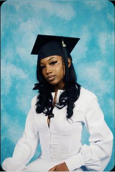 a woman wearing a graduation cap and gown posing for a photo in front of a blue background