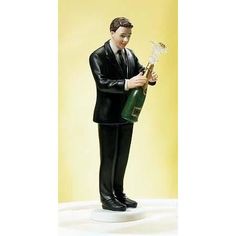 a figurine of a man in a suit holding a wine bottle and corkscrew