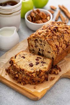 a loaf of bread sitting on top of a cutting board next to bowls of nuts