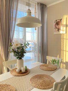 a dining room table with placemats and flowers on it in front of a window