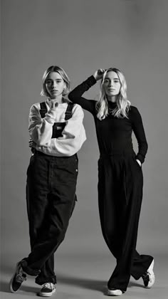 two women standing next to each other in black and white