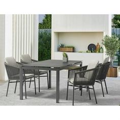 an outdoor dining table and chairs set up in front of a white wall with columns