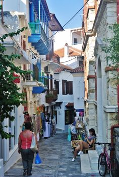 two people walking down an alley way with shops