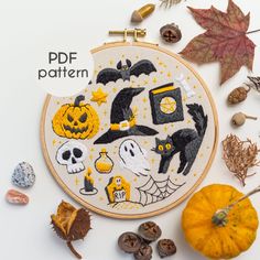 an embroidery pattern with halloween decorations and pumpkins on the side, surrounded by autumn leaves