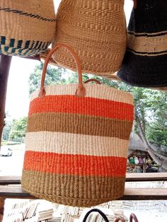 This is an African Sisal and Leather handbag or Planter Handmade in Kenya. It's made from Sisal Fibers and dyed in using natural dyes. It can be made with or without the leather handles depending on preference and use. Planters usually have the leather handles. It is used as a carry on handbag for your laptop, books or for clothes for an overnight stay.  Larger ones can be used for organizing your living room as storage for shawls or books. Larger ones can also be used as laundry baskets. They c Handmade Orange Straw Bag For Shopping, Handmade Orange Shoulder Bag For Market, Orange Basket Bag For Everyday Use, Handmade Orange Bag For Market, Multicolor Jute Basket Beach Bag, Handmade Orange Bag, Handwoven Orange Bags For Market, Orange Handwoven Bag For Market, Orange Woven Bucket Bag