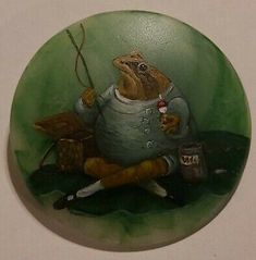 a glass plate with a frog holding a fishing rod in it's hand and sitting on the ground