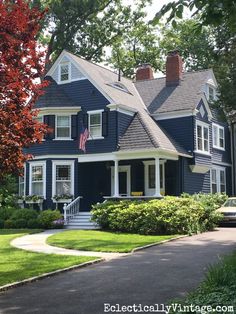 a blue house with an american flag on the front porch and two story dorme