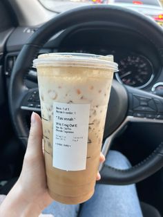 a person holding up a drink in their hand while sitting in the driver's seat