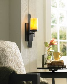 a candle is lit on the wall next to a table with books and a coffee cup