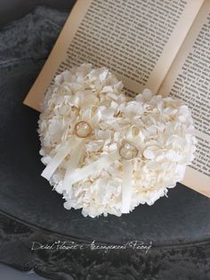 a heart shaped brooch sitting on top of an open book