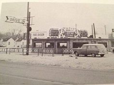 an old car parked in front of a drive - in restaurant on a snowy day