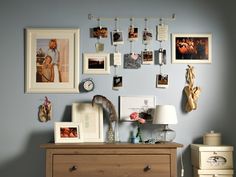 a wall with many pictures hanging on it's sideboard and a lamp next to the dresser