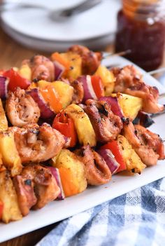 several skewers of meat and vegetables on a white plate with a blue checkered table cloth