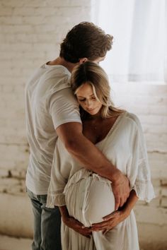 a man and woman standing next to each other in front of a white brick wall