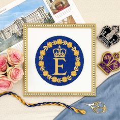 the letter e is surrounded by flowers and other decorative items, including brooches