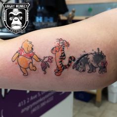 winnie the pooh and tigger tattoos on someone's left arm, both with different colors