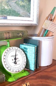 a green clock sitting on top of a wooden table next to books and pencils