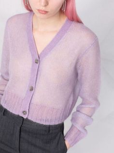 a woman with pink hair wearing a purple cardigan