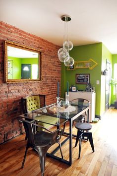 a dining room table and chairs in front of a brick wall with a mirror on it