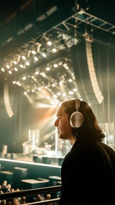 a man with headphones standing in front of an auditorium full of people and looking at the stage