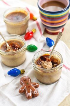 two jars filled with food sitting on top of a white table cloth next to small cookies