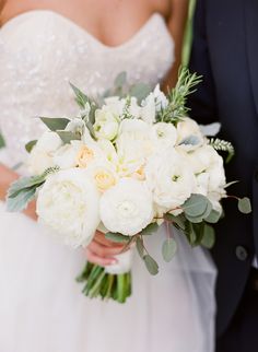 a bride and groom holding a bouquet of white flowers in their hands at the end of their wedding day