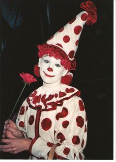 a clown is holding a flower in his hand