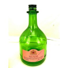 a green bottle filled with liquid sitting on top of a white tablecloth covered floor