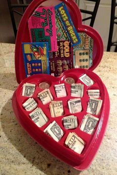 a red heart shaped box filled with lots of cards and money sitting on top of a counter