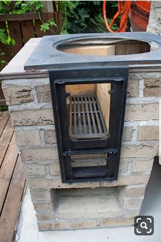 an outdoor oven built into the side of a brick wall with a grill on top