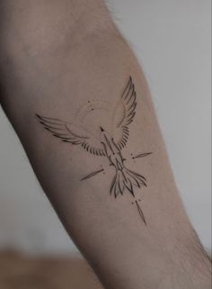 a small tattoo on the arm of a man with a bird flying over it's shoulder