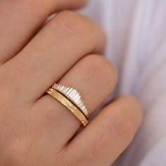 a woman's hand wearing a gold and white ring with two feathers on it